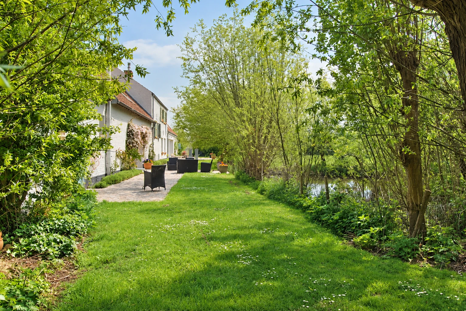 Dat wäisst Haus lénks, d’Terrass an de Weier riets tëscht de Weiden