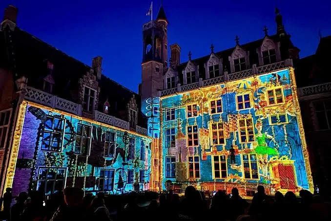 Farbenfrohe Lichtprojektion auf einer historischen Fassade in Brügge