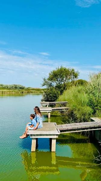 Waasser a Riet mat enger hëlzener Plattform, op där Leit sëtzen