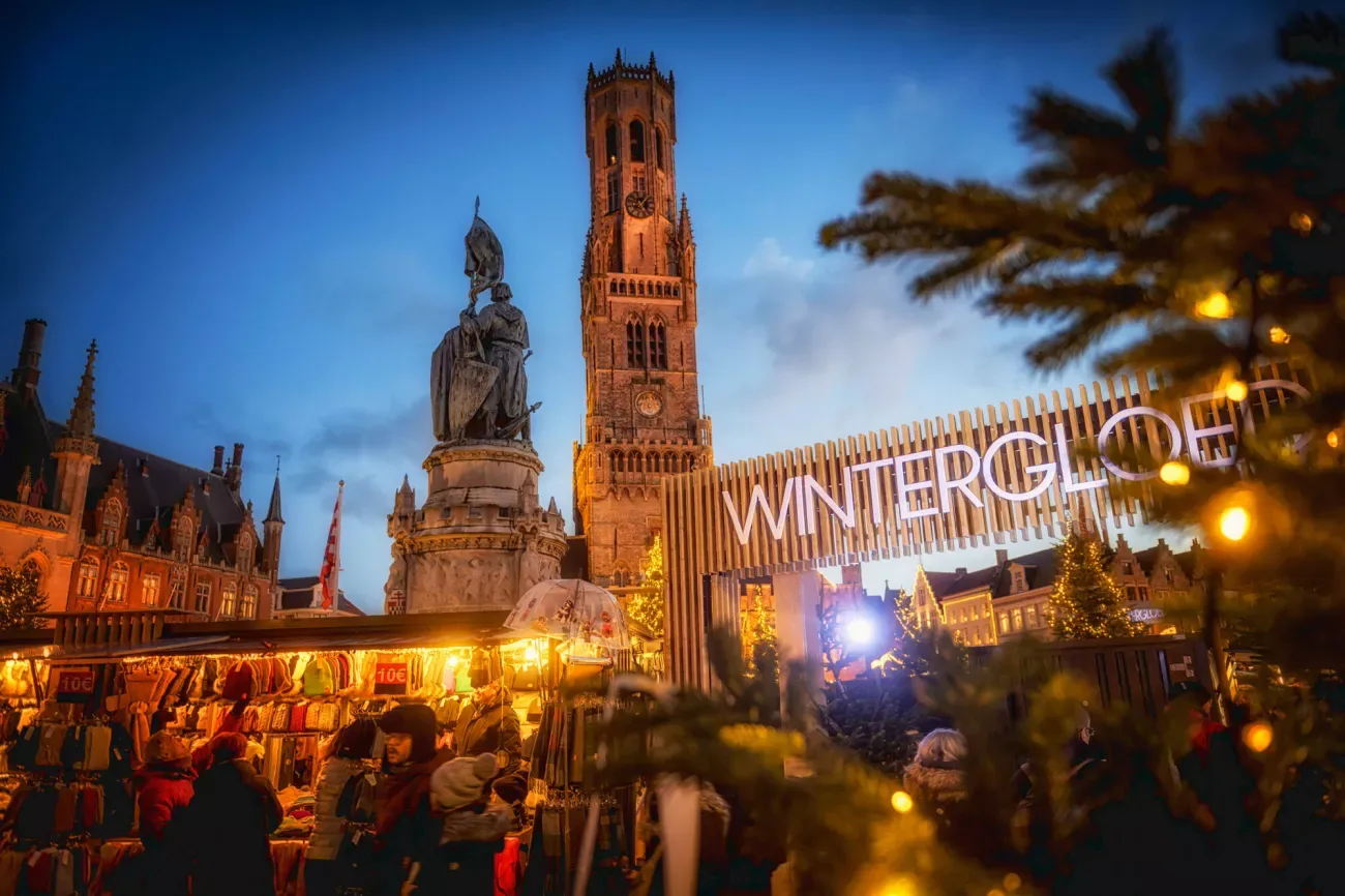 Eingang zum Wintergloed-Weihnachtsmarkt mit dem Belfried im Hintergrund