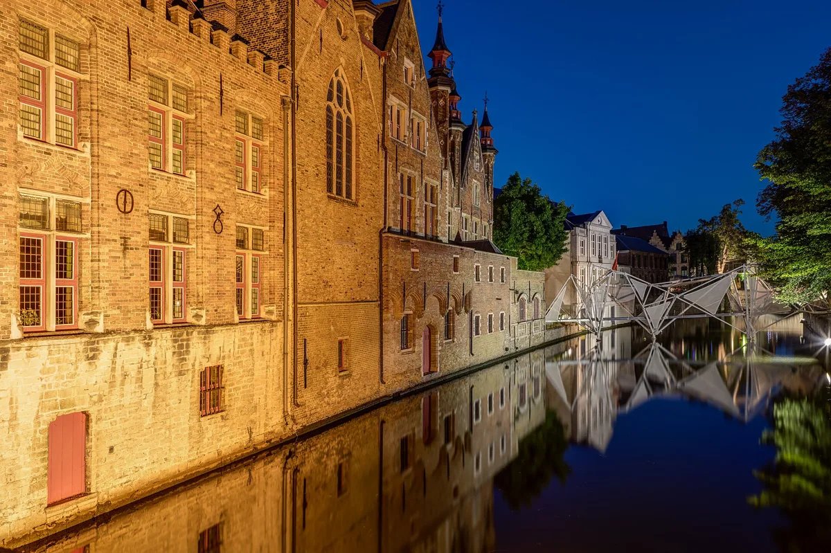Historesch Fassaden, déi sech am Owesliicht an der Groenerei zu Brugge spigelen