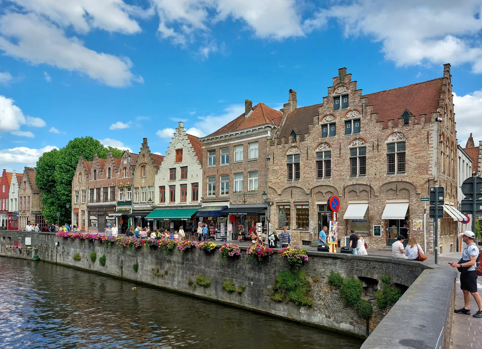 Träppchegiewelen an Terrasse beim Rozenhoedkaai zu Brugge, mat Blummekëschten iwwer dem Kanal